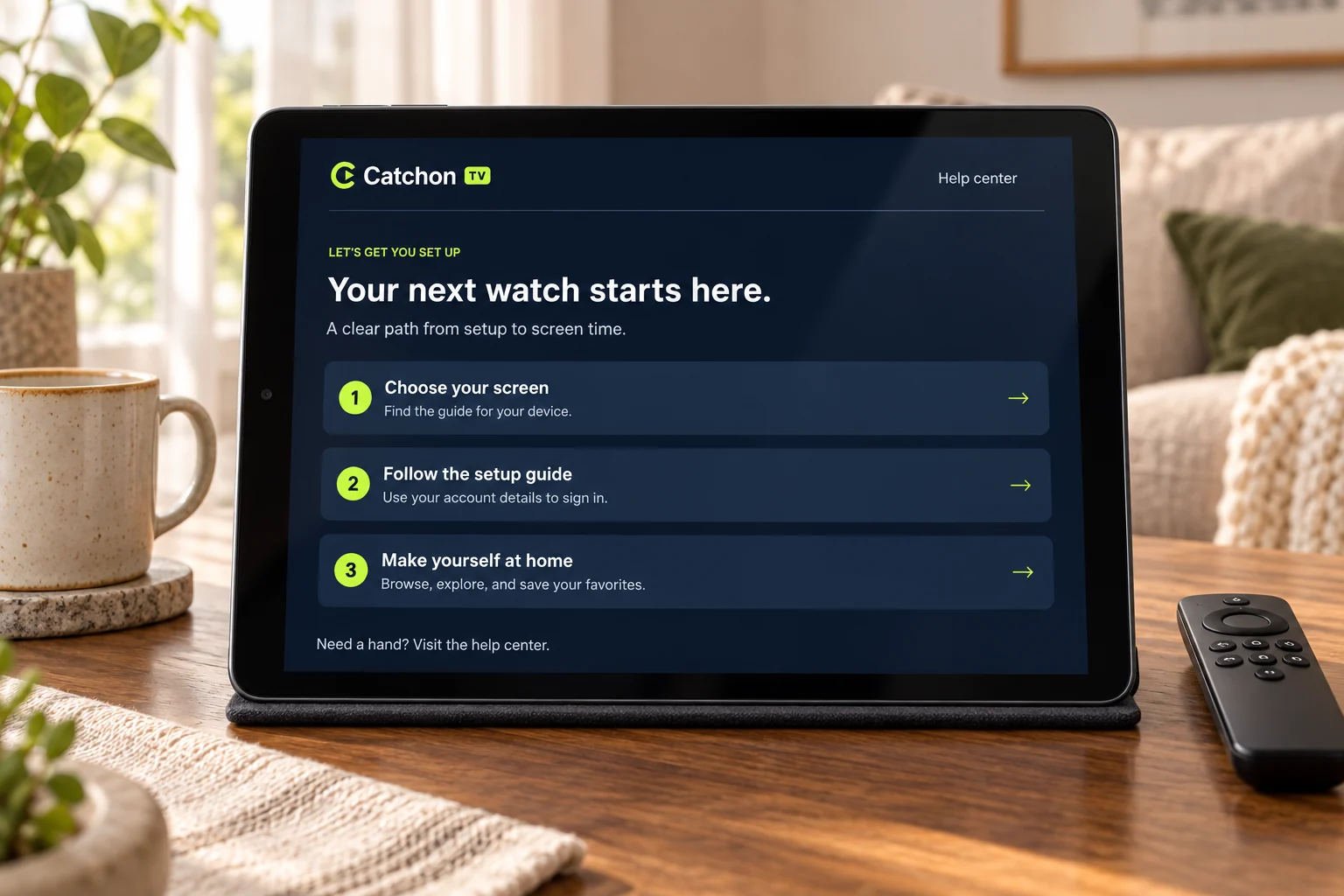 A tablet showing the Catchon TV setup guide beside a mug and a television remote.